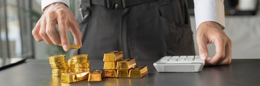 investor calculating the worth of gold bars and coins